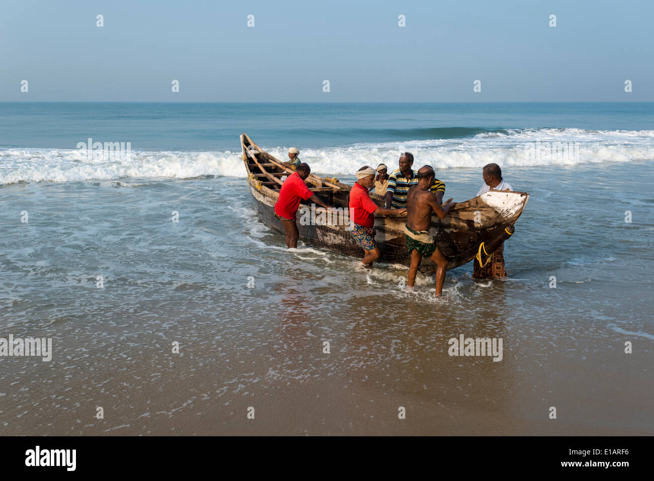 Fishermen pushing a boat onto the beach, Varkala, Kerala, India Stock Photo