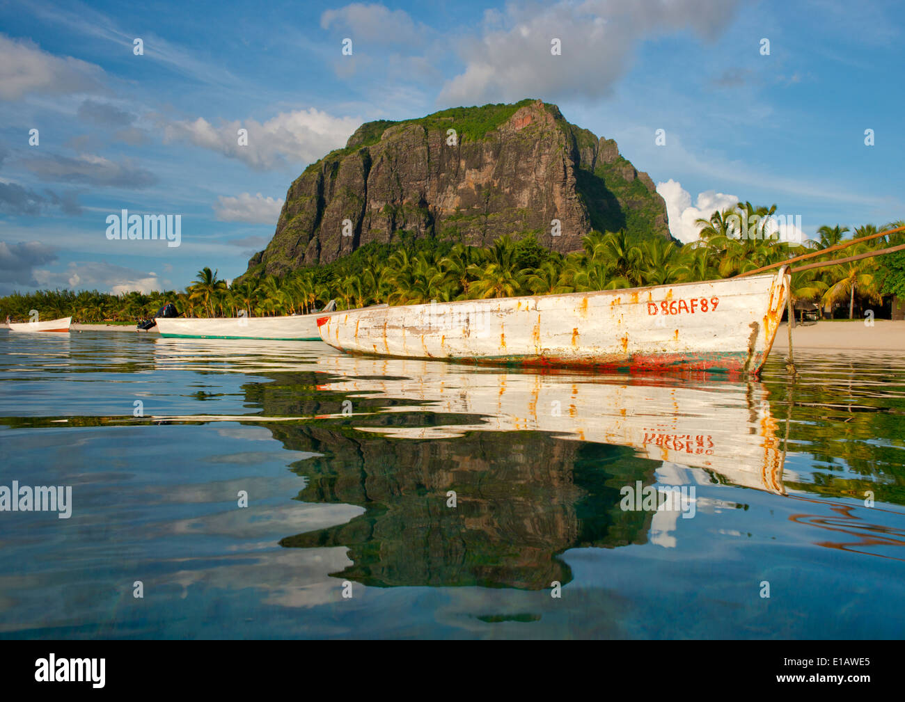 An old wooden fishing boat in calm sea in front of Le Morne Brabant on Mauritius, The Indian Ocean Stock Photo