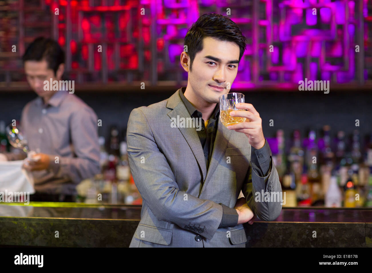 Young man having a drink at bar Stock Photo