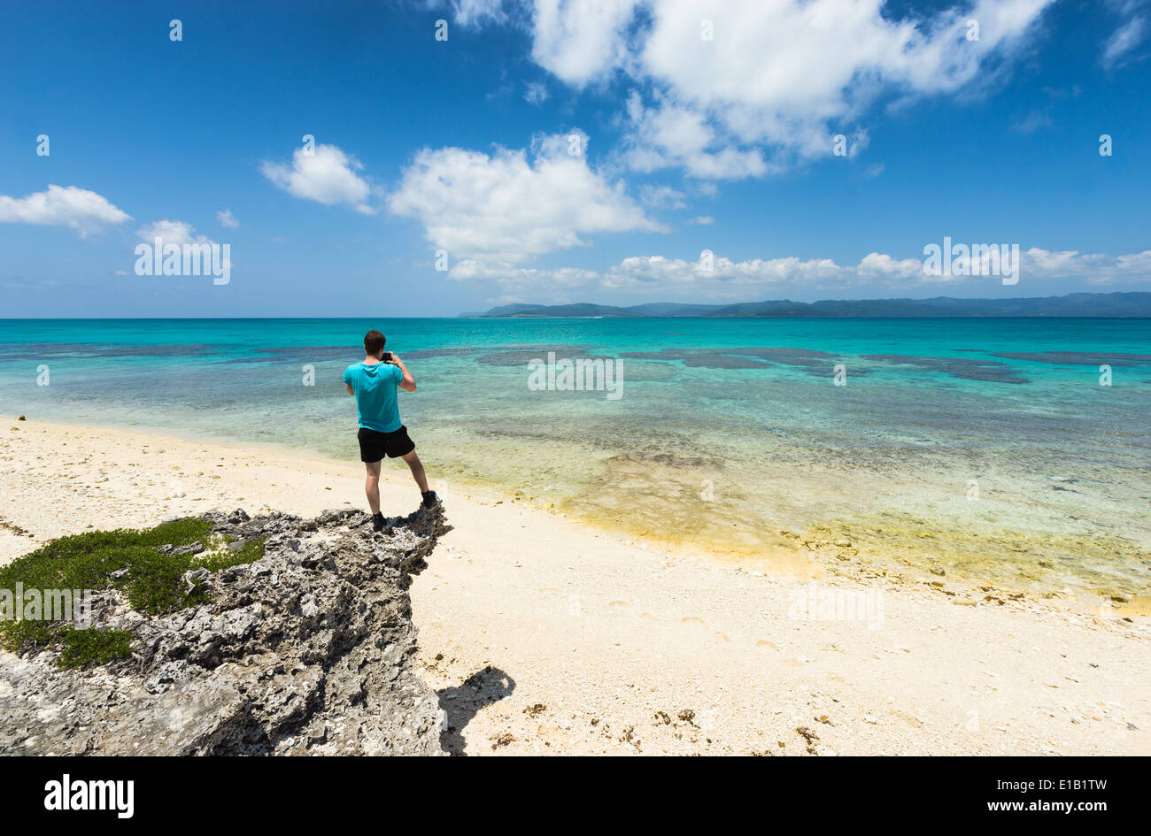 Man taking photo of stunning white sand tropical beach full of healthy coral, Yaeyama islands, Okinawa, Japan Stock Photo