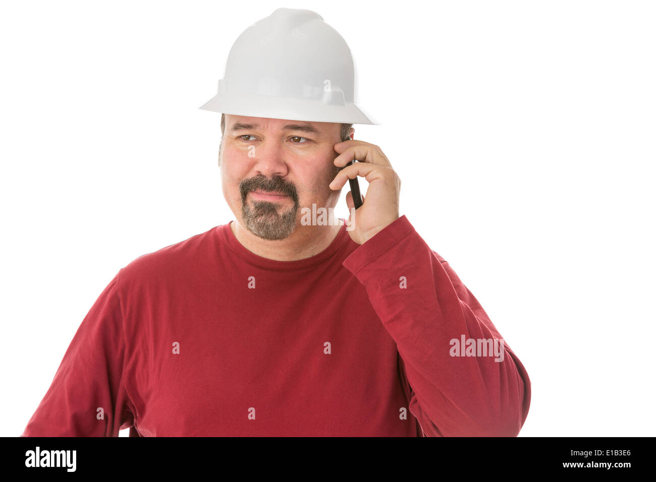 Bored looking workman, engineer or architect chatting on his mobile looking away with a thoughtful wry expression as he listens Stock Photo