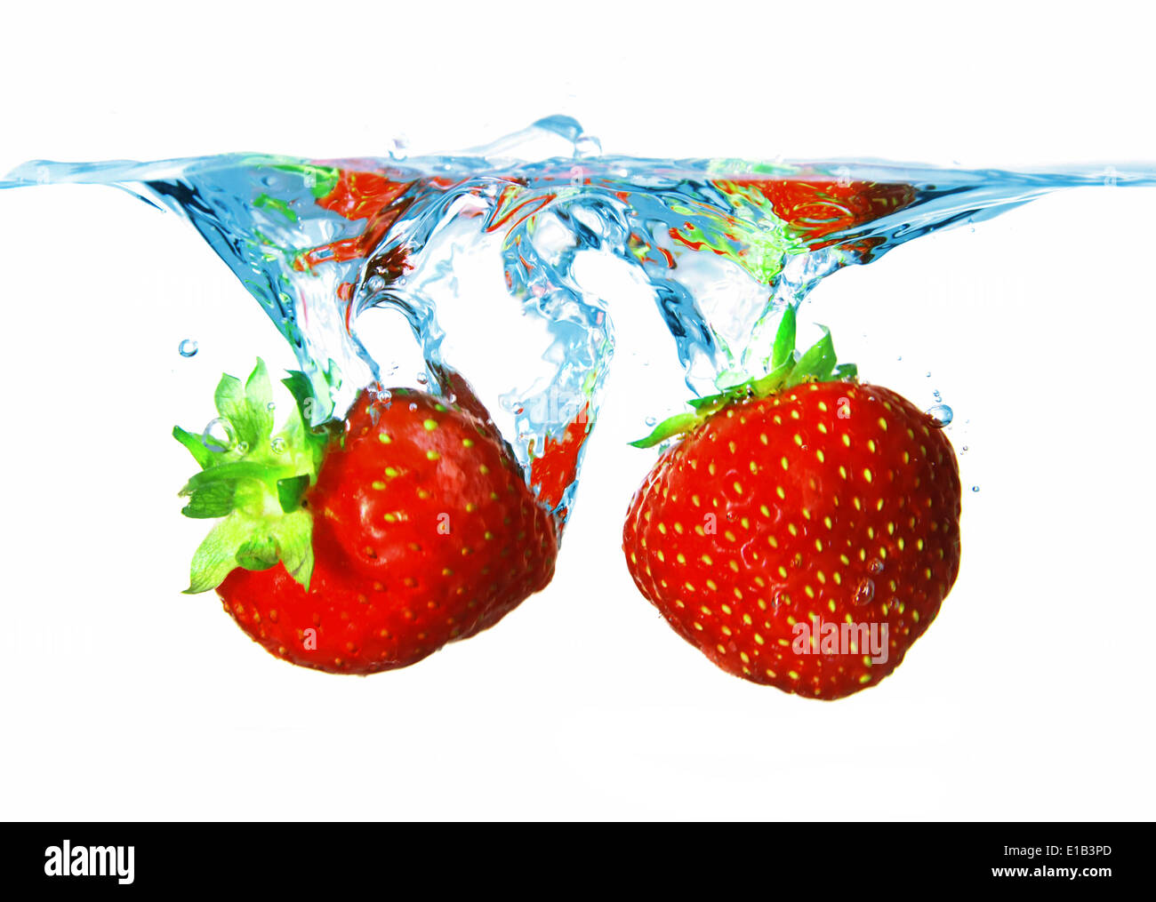 Water splash of two ripe beautiful red strawberries Stock Photo