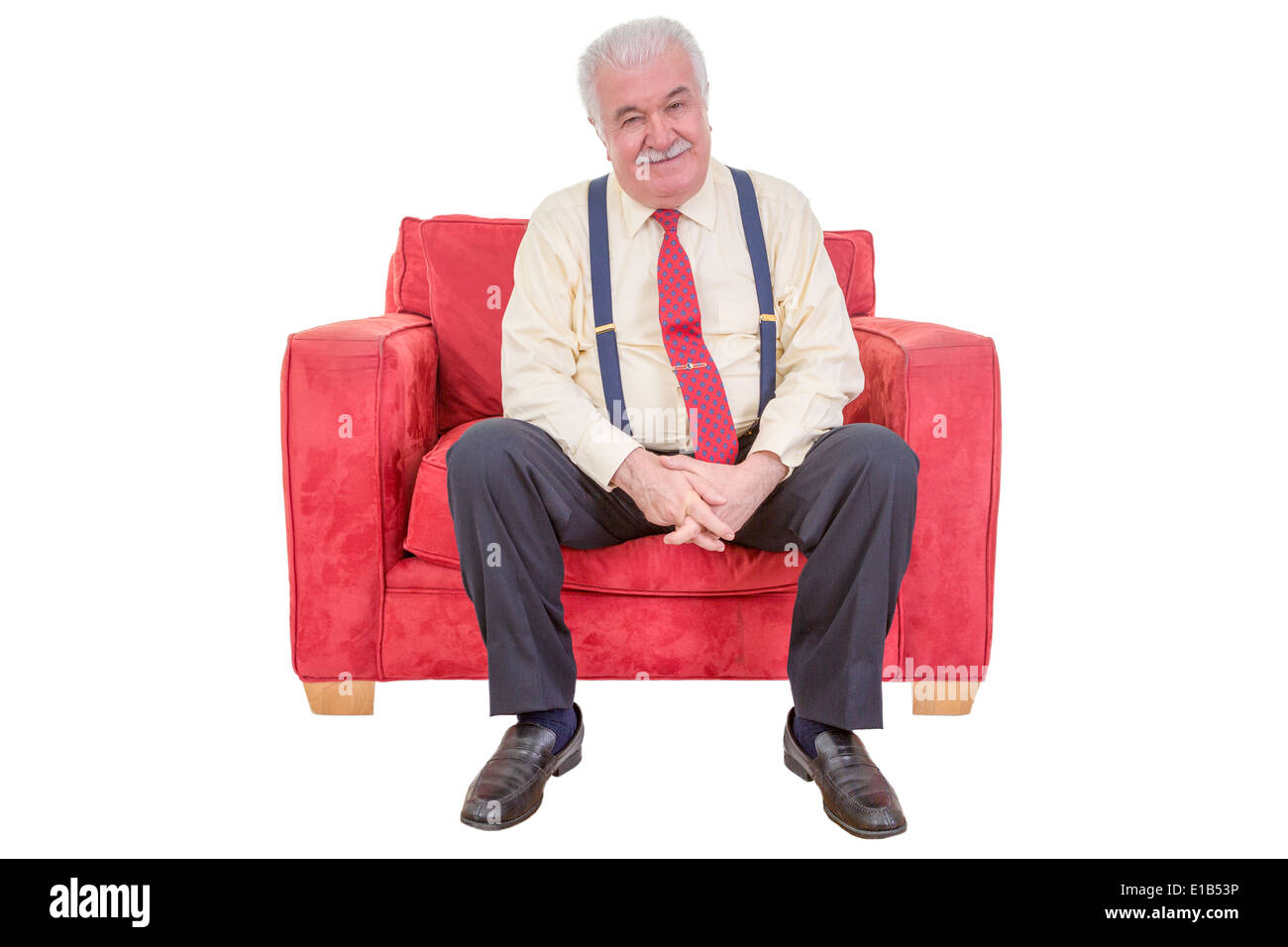 Studio portrait over white of a senior white haired man relaxing in a comfortable red armchair. Stock Photo