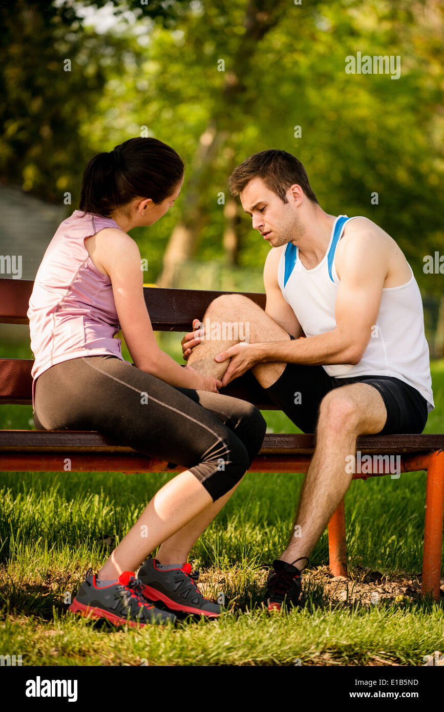 Woman helps to man who injured his calf when jogging Stock Photo
