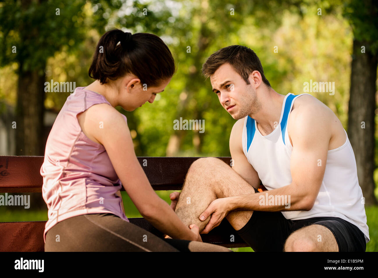 Woman helps to man who injured his calf when jogging Stock Photo