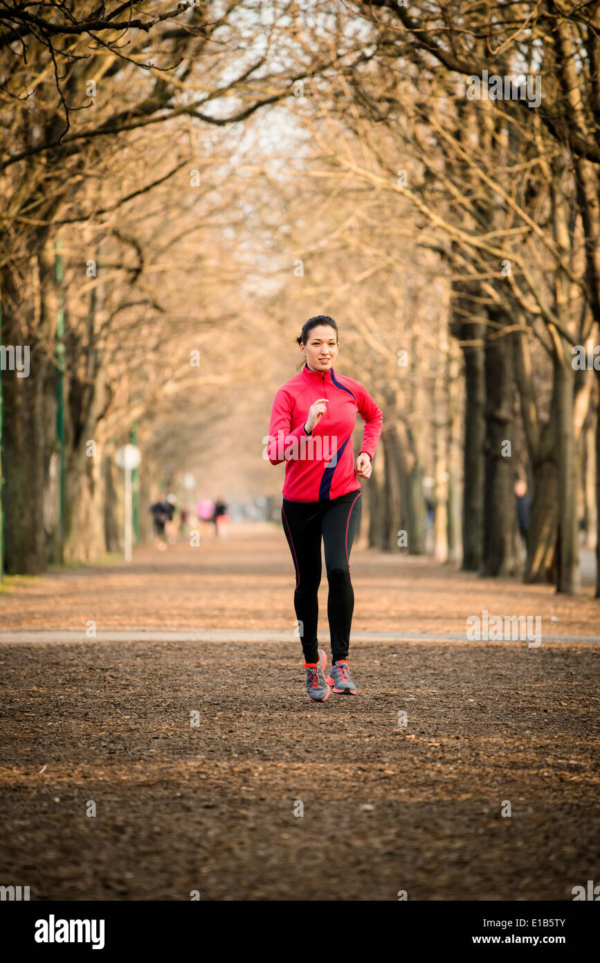 Young woman jogging in tree alley - late autumn Stock Photo