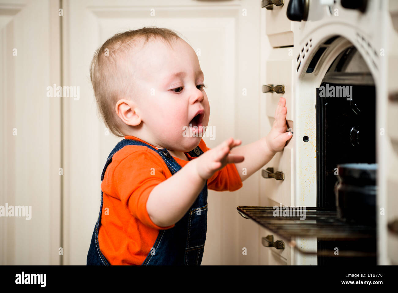 Dangerous situation - little baby opened kitchen oven Stock Photo
