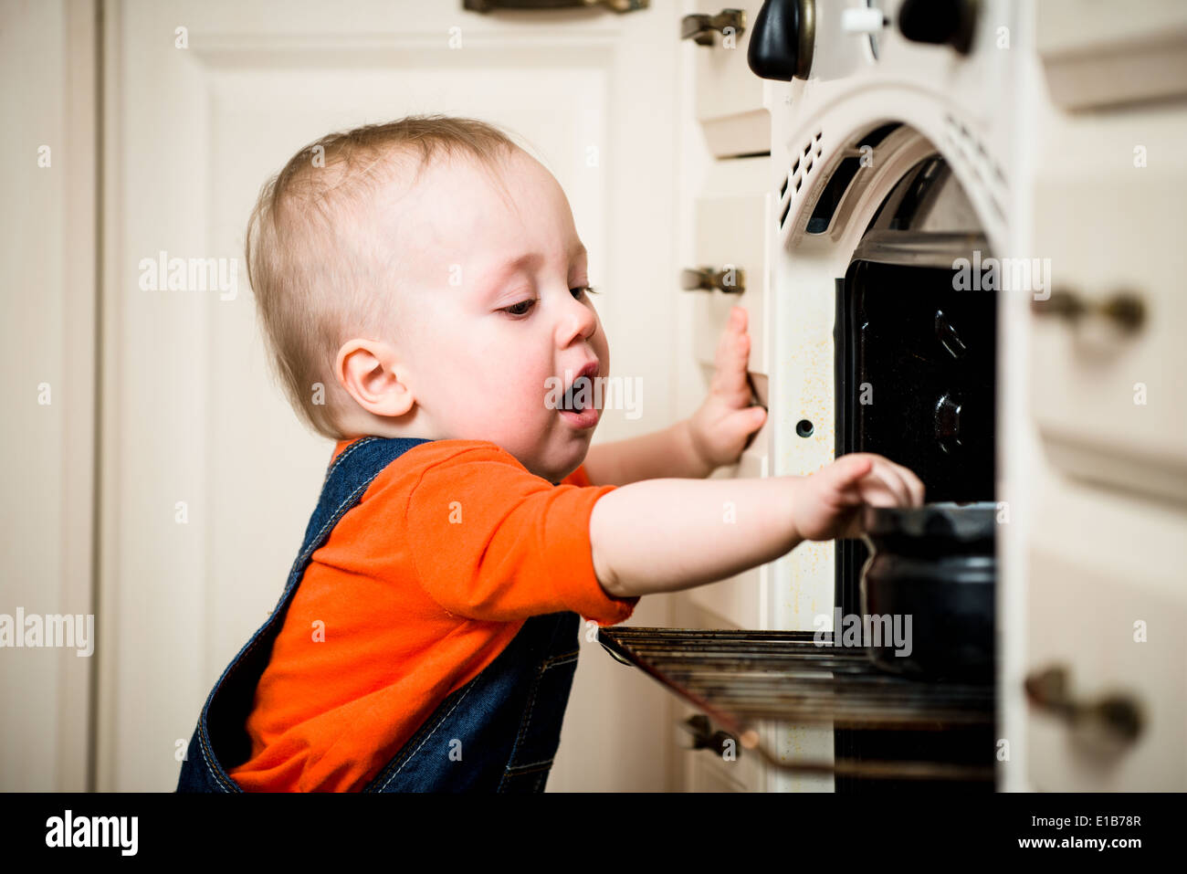 Dangerous situation - little baby opened kitchen oven Stock Photo