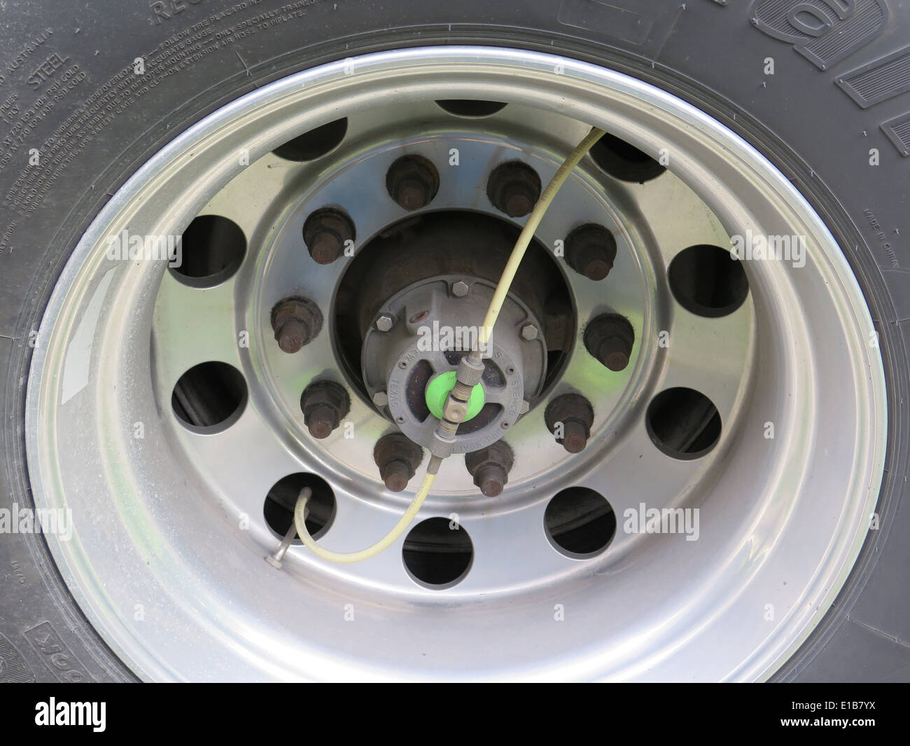 Large tanker truck wheel and tire with brake hose visible. Stock Photo