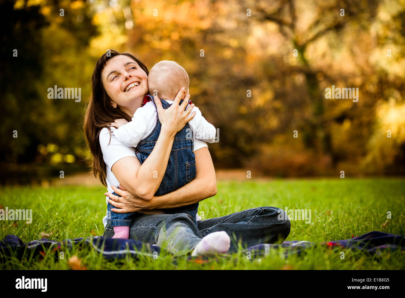 Happy mother holding her baby - sitting outdoor in nature Stock Photo
