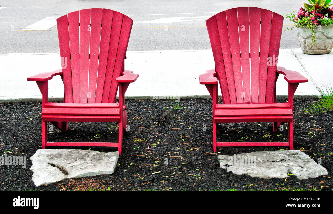 Two red garden chairs and two stone footrests Stock Photo