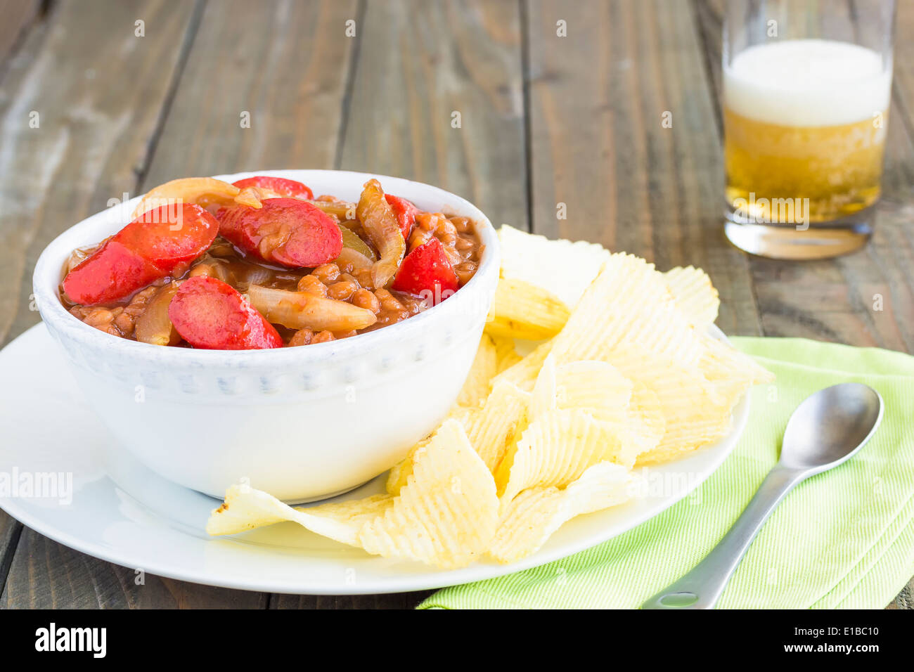 Brown sugar pork and beans with Maui sweet onions and Hawaiian paprika hot dogs, served with potato chips Stock Photo