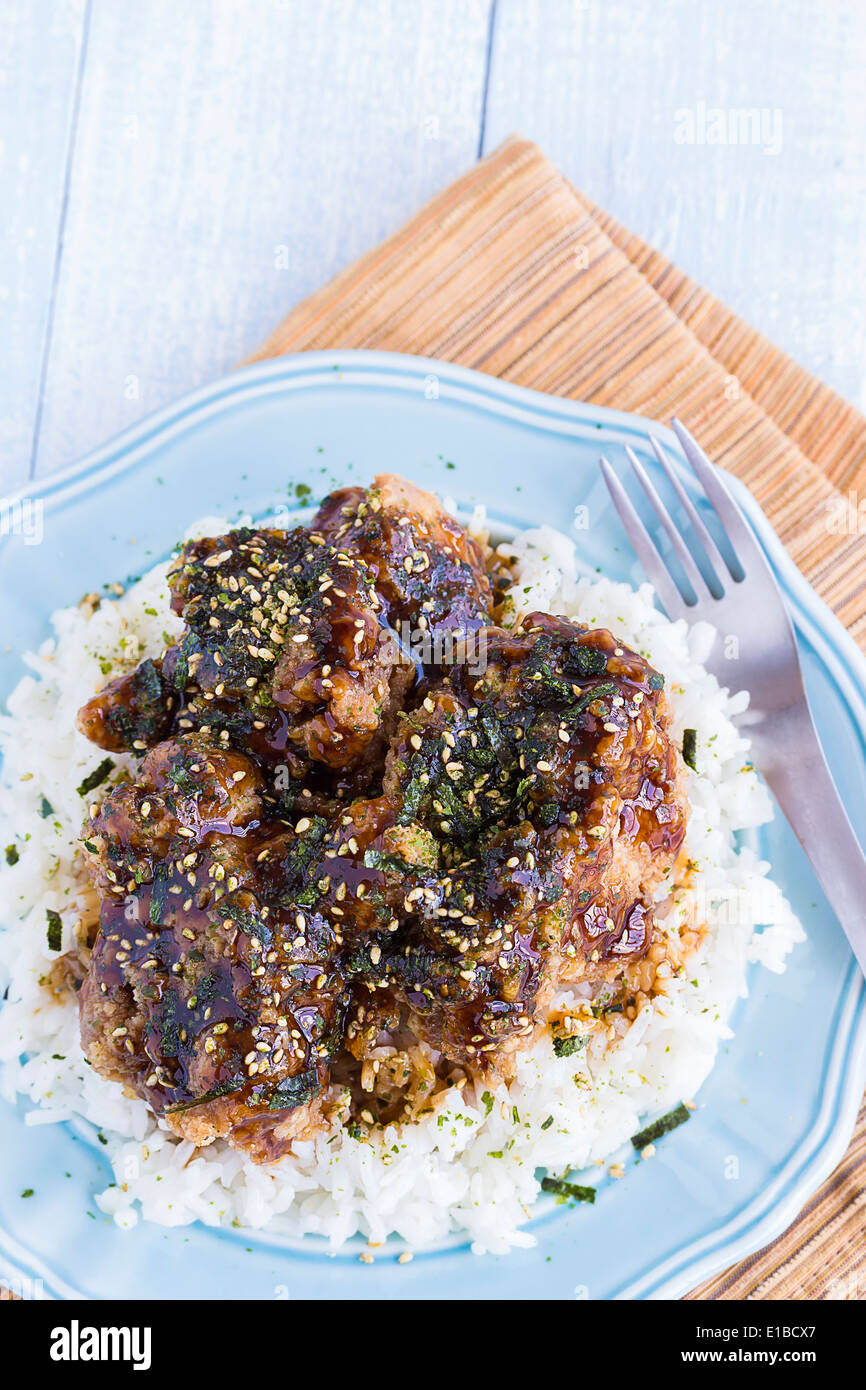 Fried chicken covered in garlic teriyaki sauce and sprinkled with furikake on a bed of rice Stock Photo