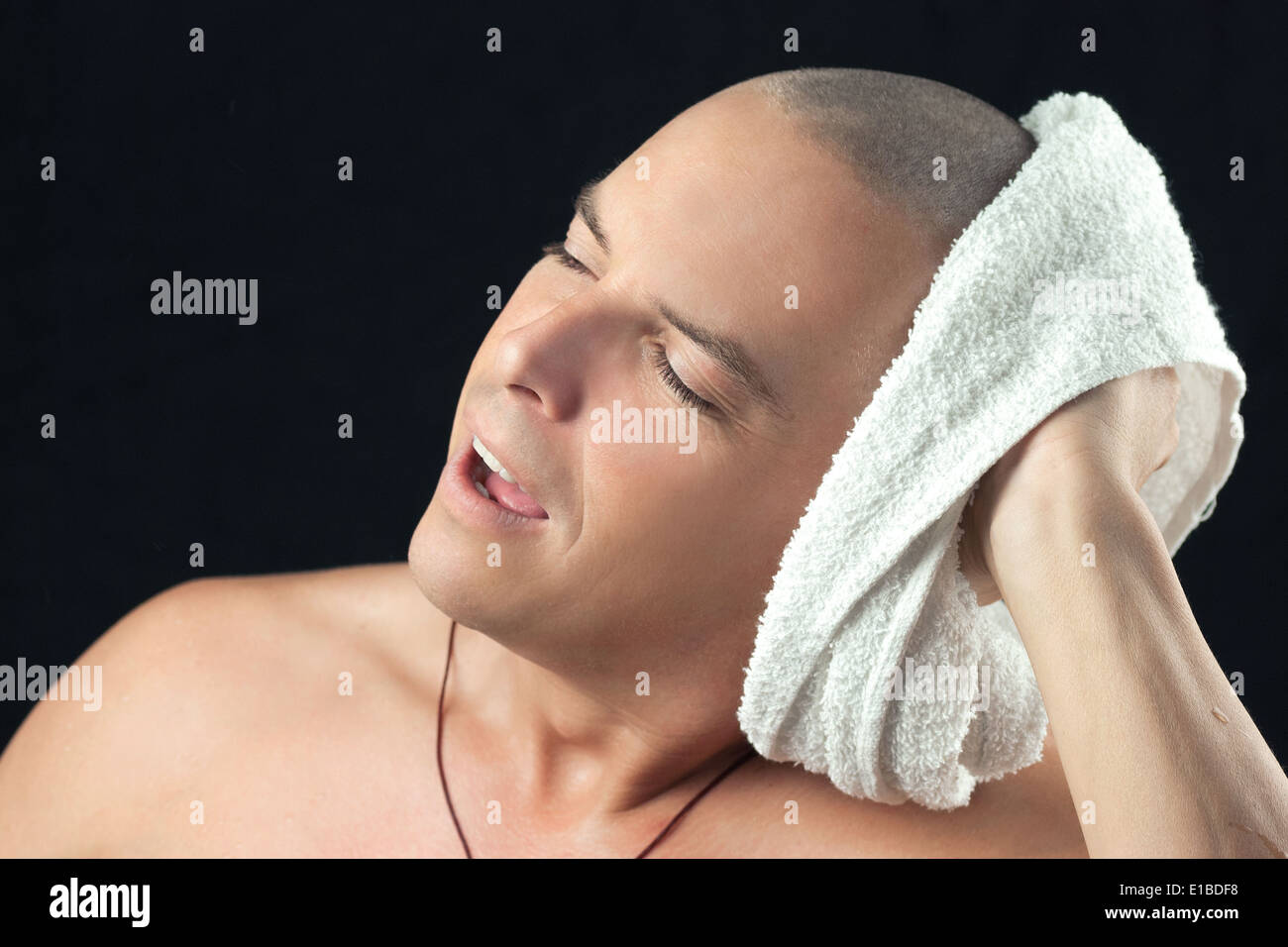 Close-up of a man towel drying his newly shaved head. Stock Photo