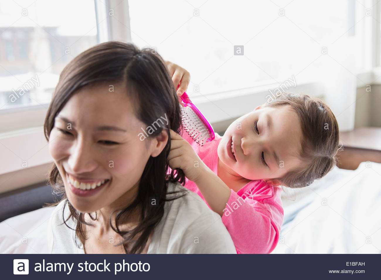 Daughter brushing mothers hair Stock Photo