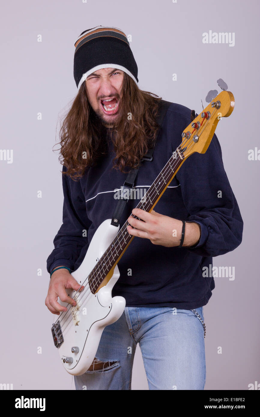 talented young musician playing hard bass guitar, isolated on gray background Stock Photo