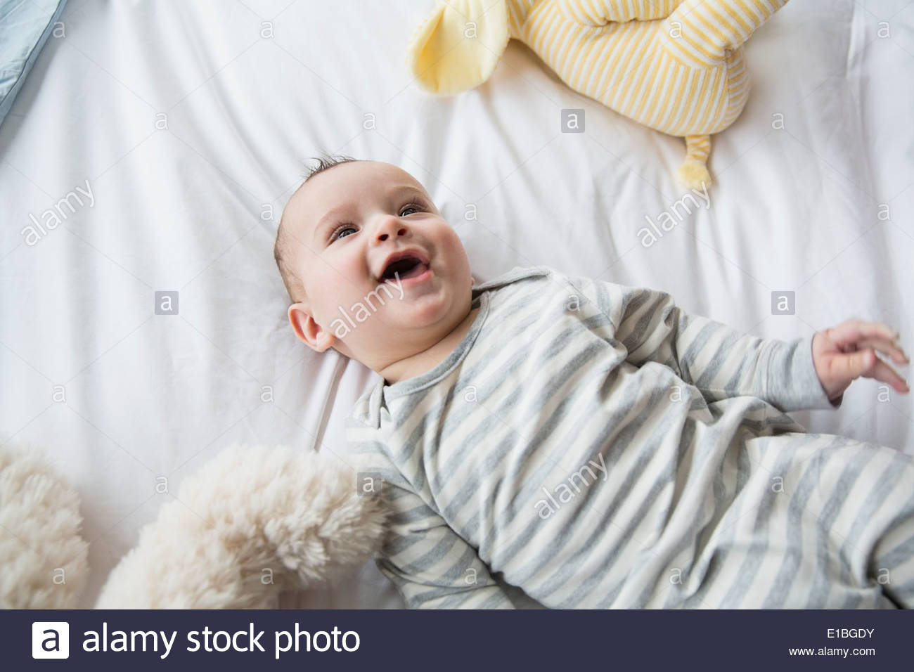 Laughing baby laying on bed Stock Photo Alamy