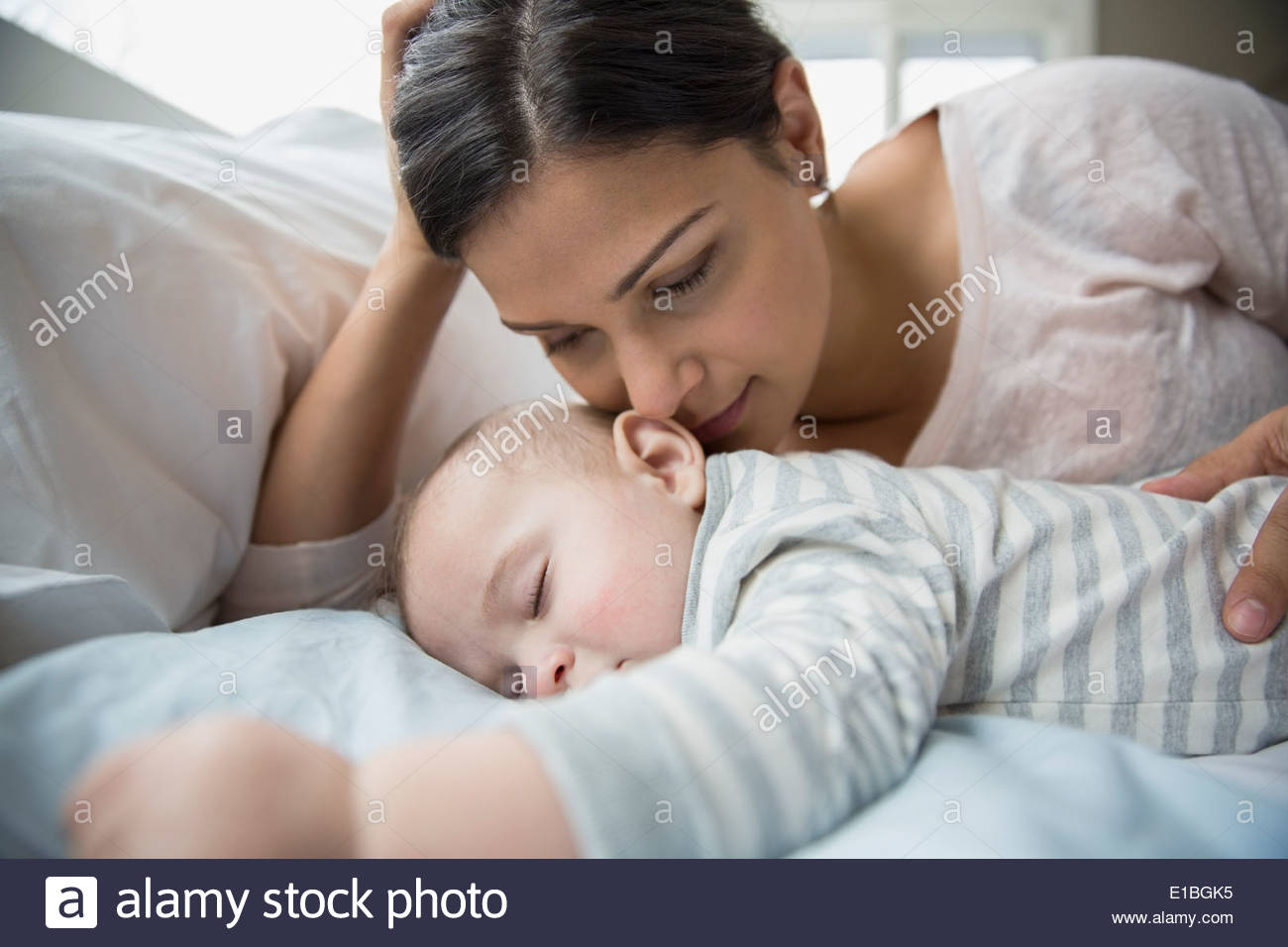 Mother watching sleeping baby on bed Stock Photo