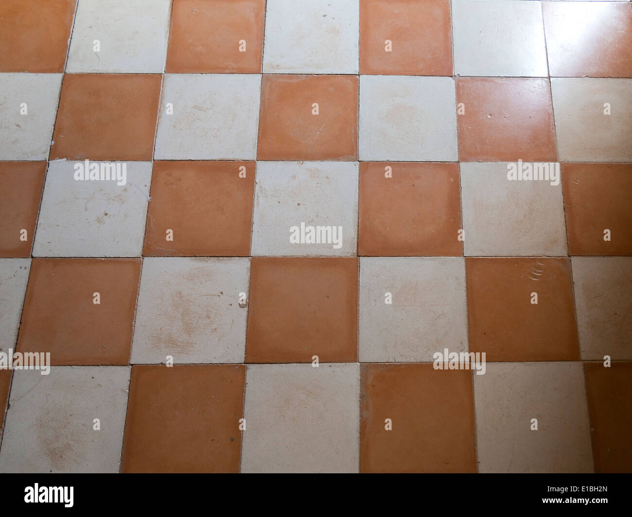 Close up of antique ceramic checkerboard tiled flooring with light shining across Stock Photo