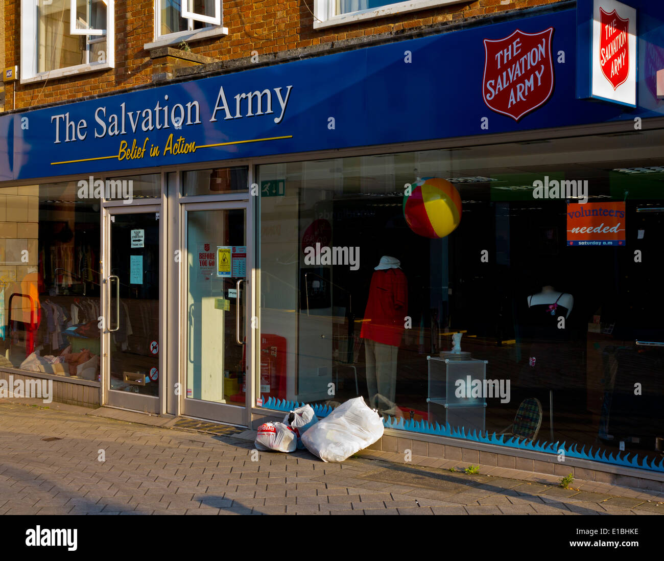 Bags of donated clothing left outside a Salvation Army high street charity shop in Redhill Surrey England UK Stock Photo