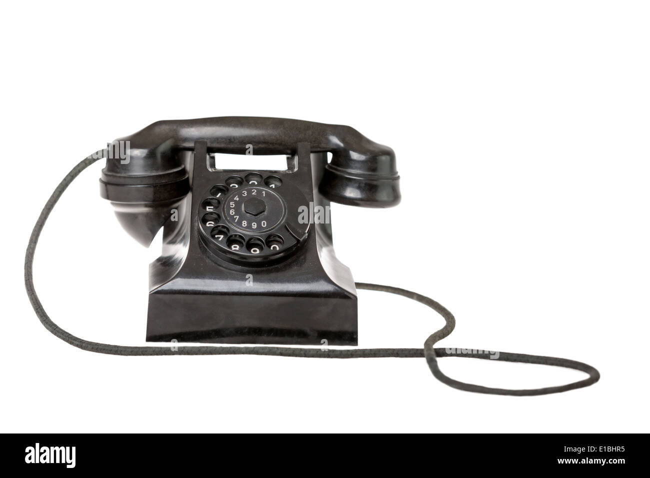 Old-fashioned black rotary telephone instrument with its handset on the cradle on white background with copy space Stock Photo