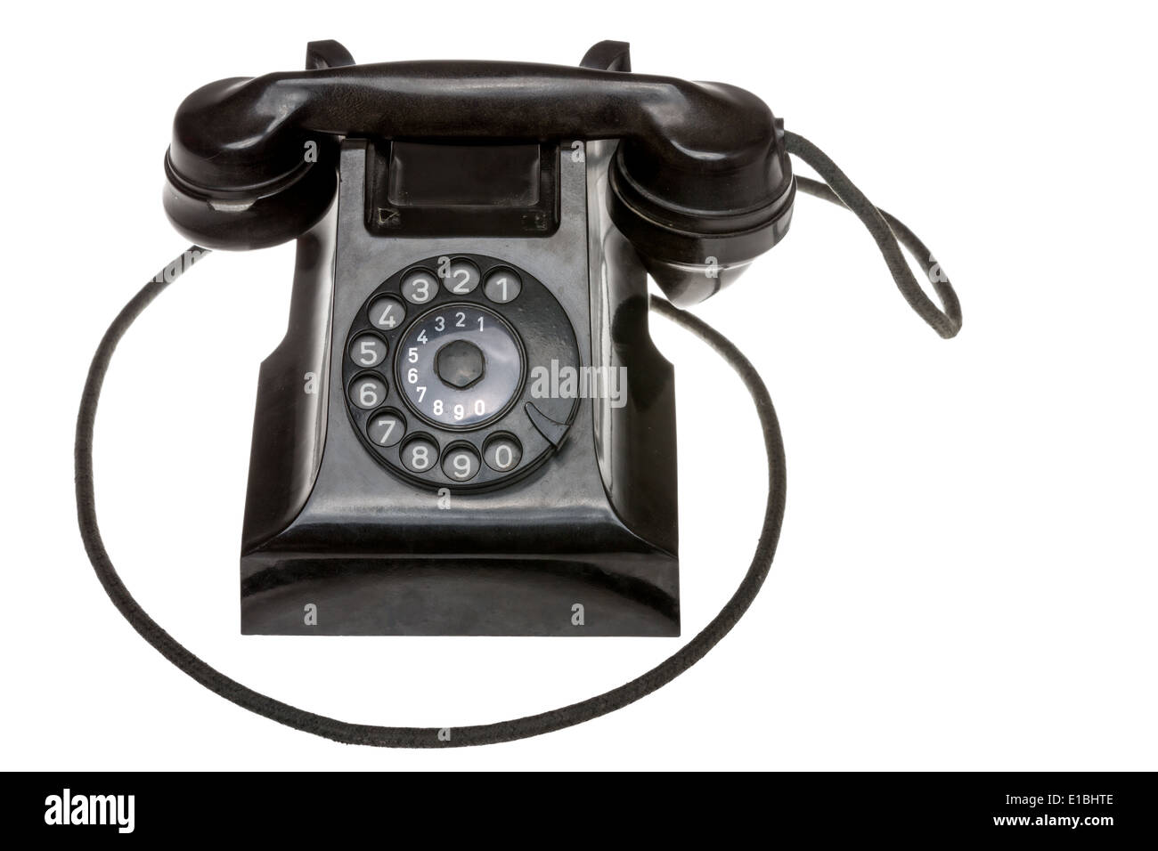 Classic old black rotary dial-up telephone instrument, closeup frontal view with the handset in place over a white studio backgr Stock Photo