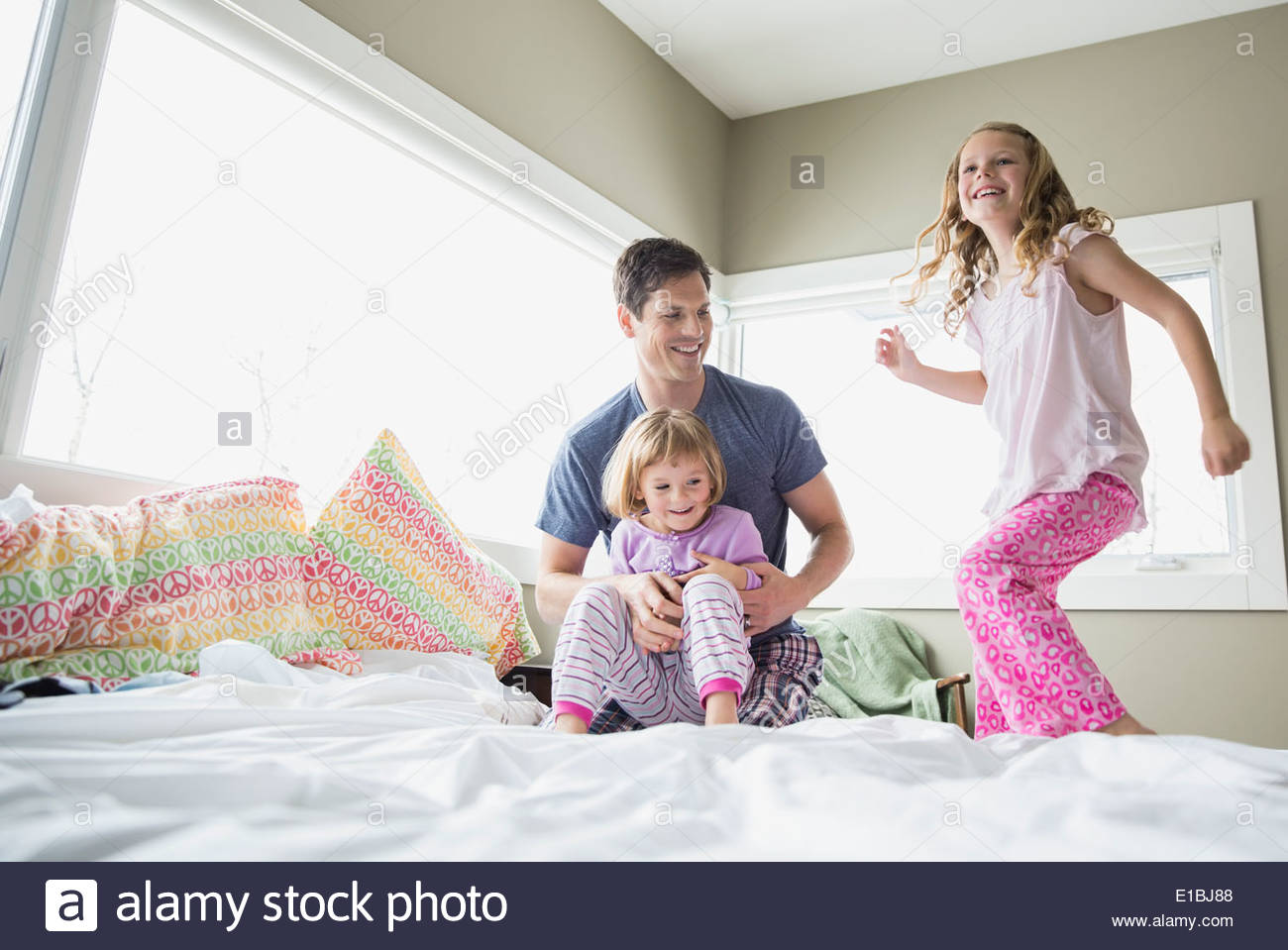Father and daughters playing on bed Stock Photo