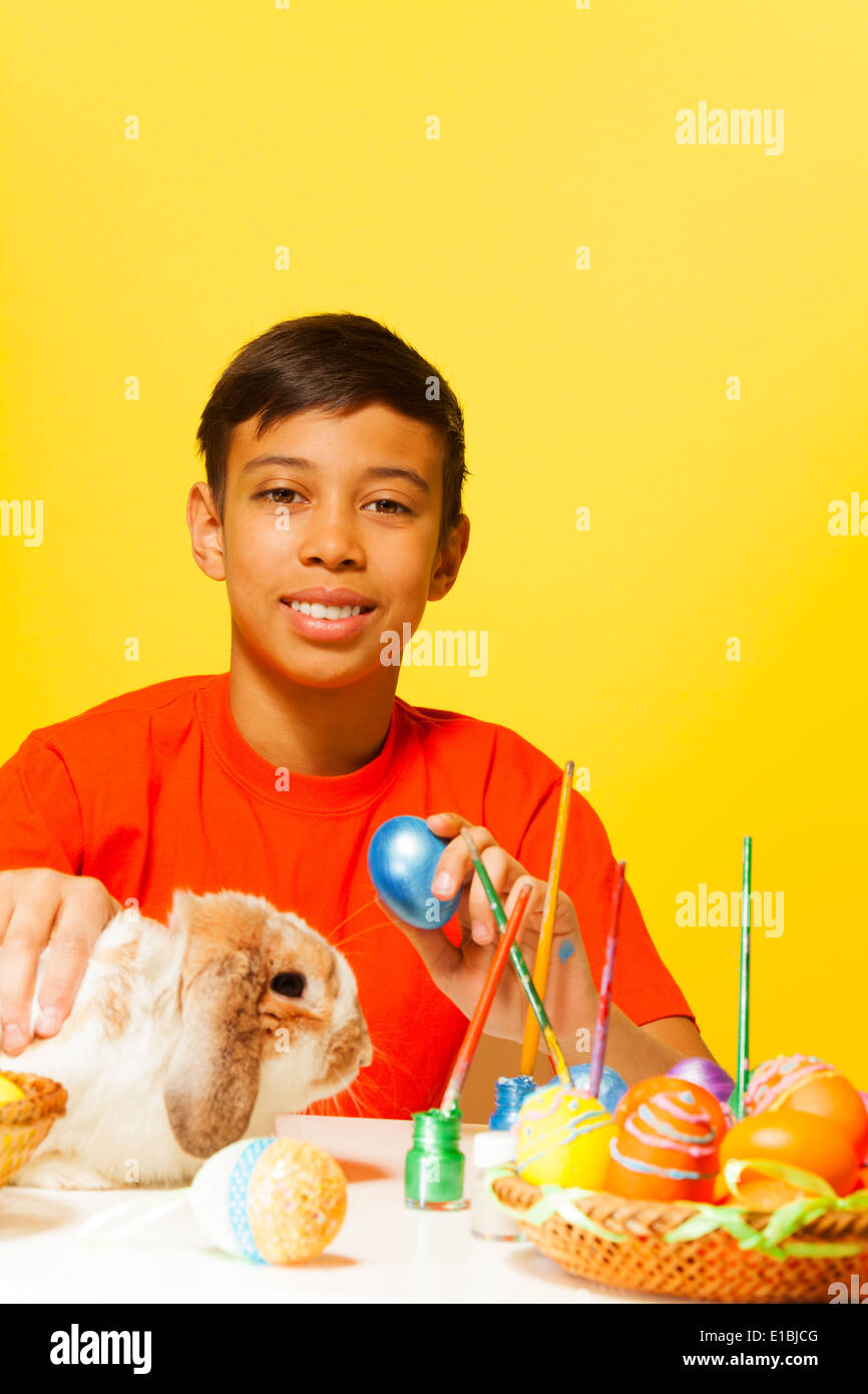 Boy with Easter eggs and cute rabbit on table Stock Photo