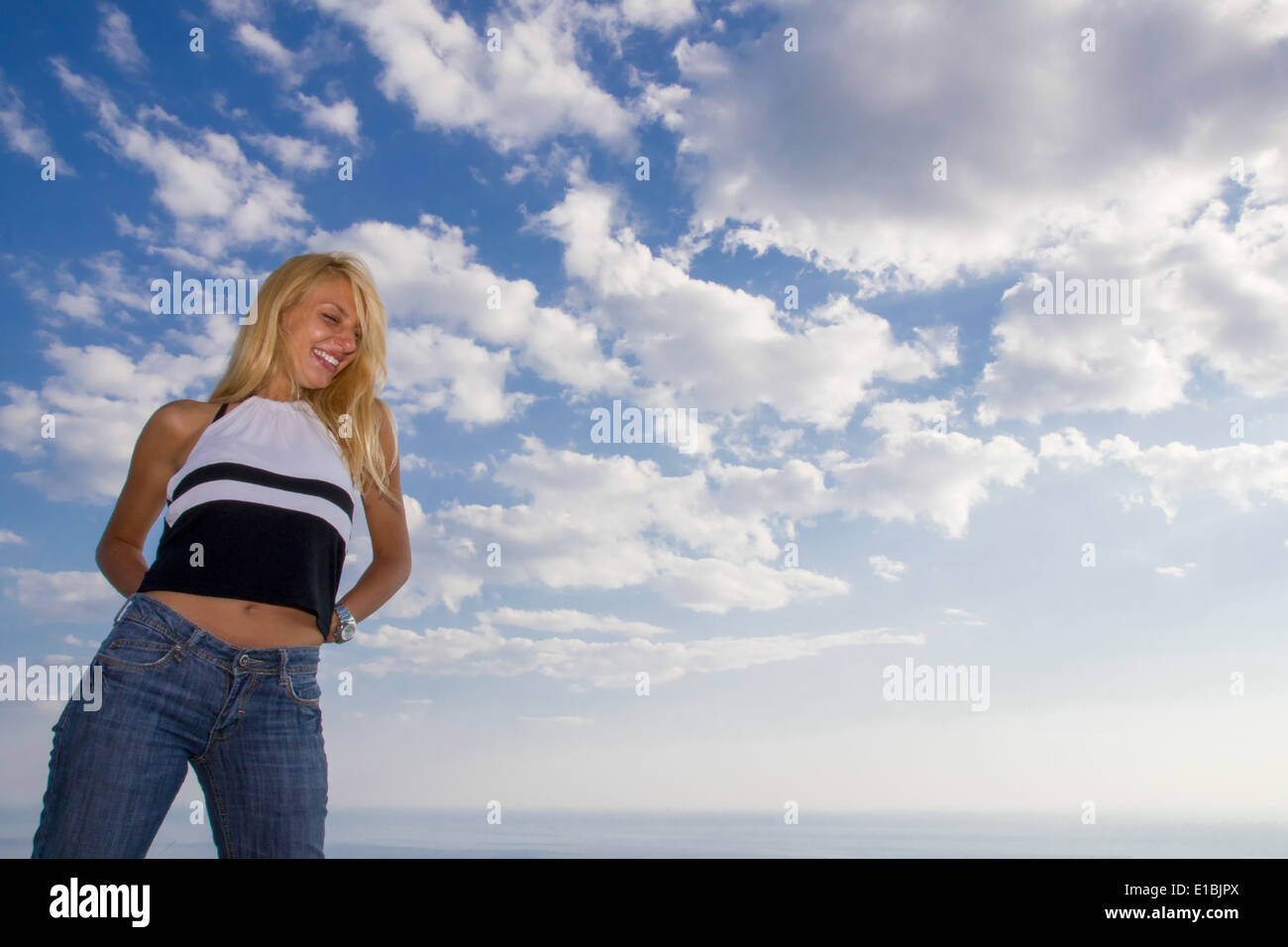 beautiful woman in front of sky next to sea Stock Photo