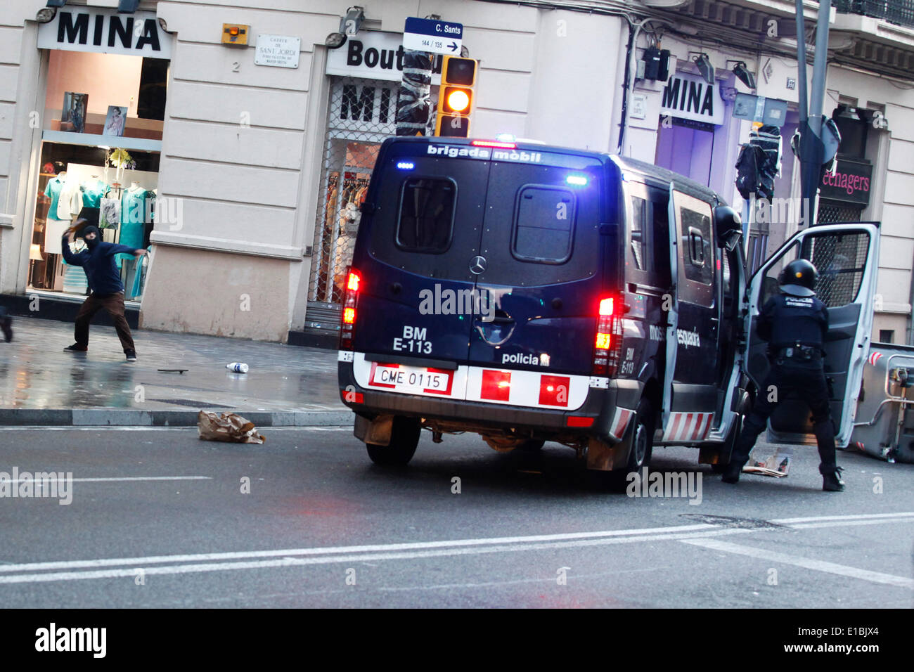Barcelona, Spain. 26th May, 2014. A protester throws a bottle to a riot police van during the protest against the eviction of 'Can Vies' in Barcelona, Spain, May 26, 2014. Clashed happened between the police and protesters in Barcelona for the eviction of activists from a well-known squat. Police had earlier evicted occupants inside the 'Can Vies', a building owned by the local transport authority but occupied since 1997 by activists who have used it as a community centre. © Pau Barrena/Xinhua/Alamy Live News Stock Photo
