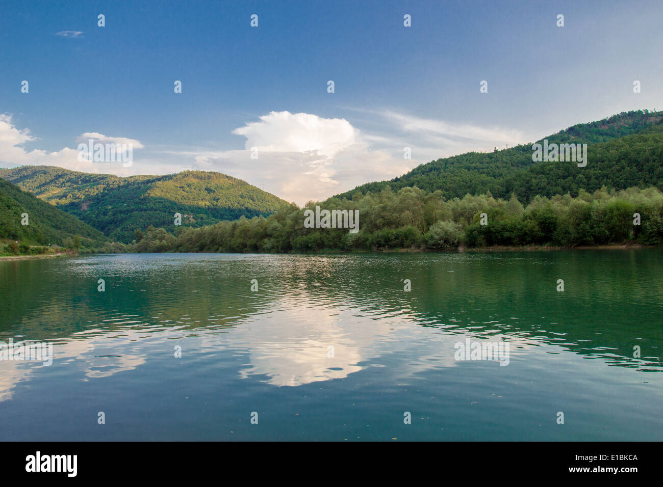 lake landscape surrounded by green hills with reflection Stock Photo