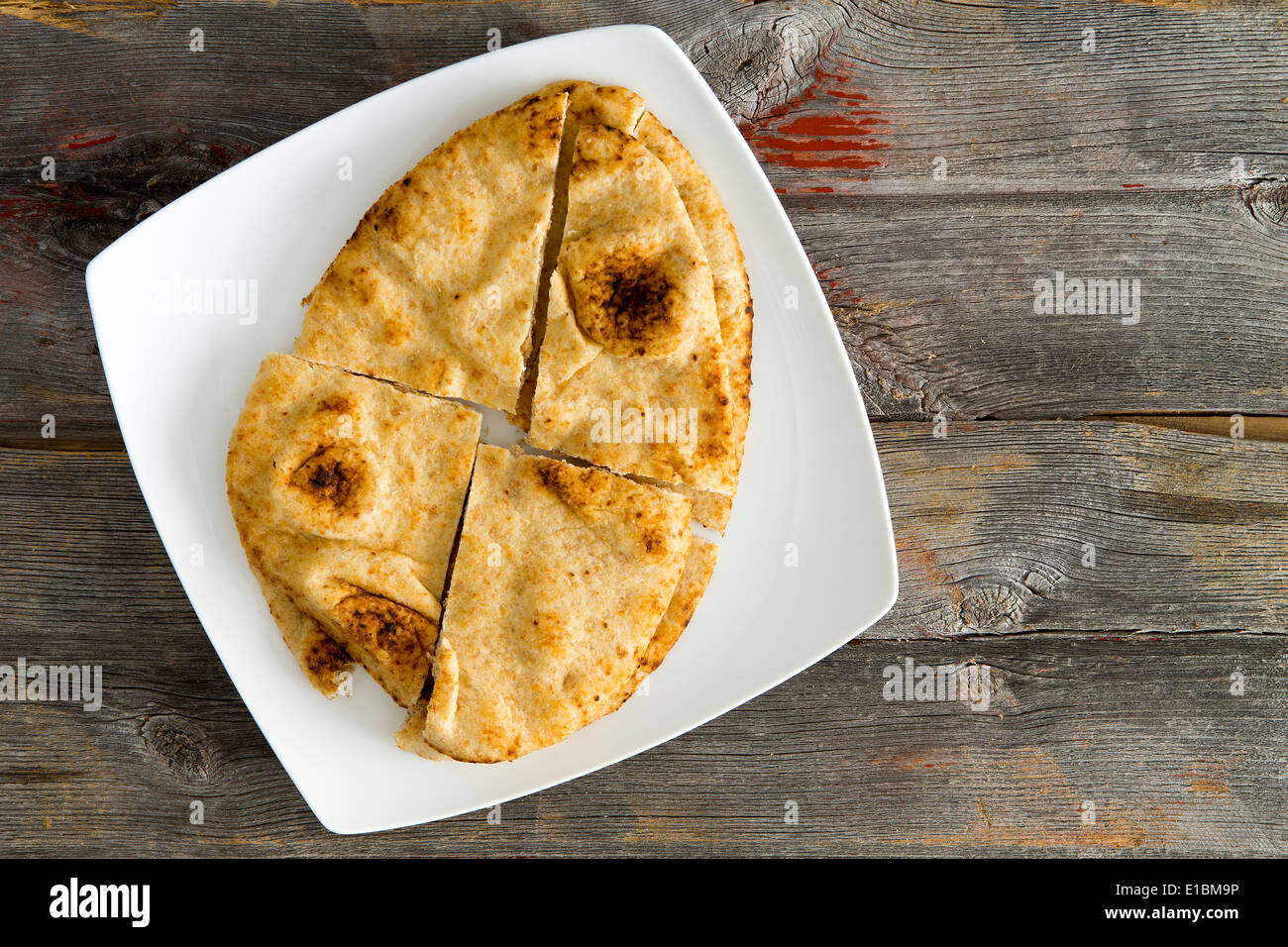 Overhead view of a crisp golden Naan flatbread baked in a traditional tandoor served on a modern