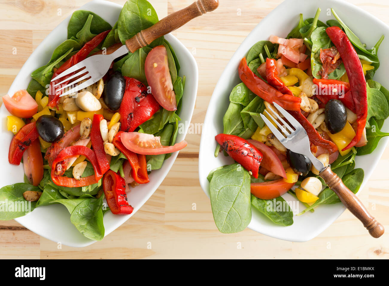 Two delicious bowls of baby spinach and cayenne or chili pepper salad served as individual appetizers or accompaniments to a hea Stock Photo