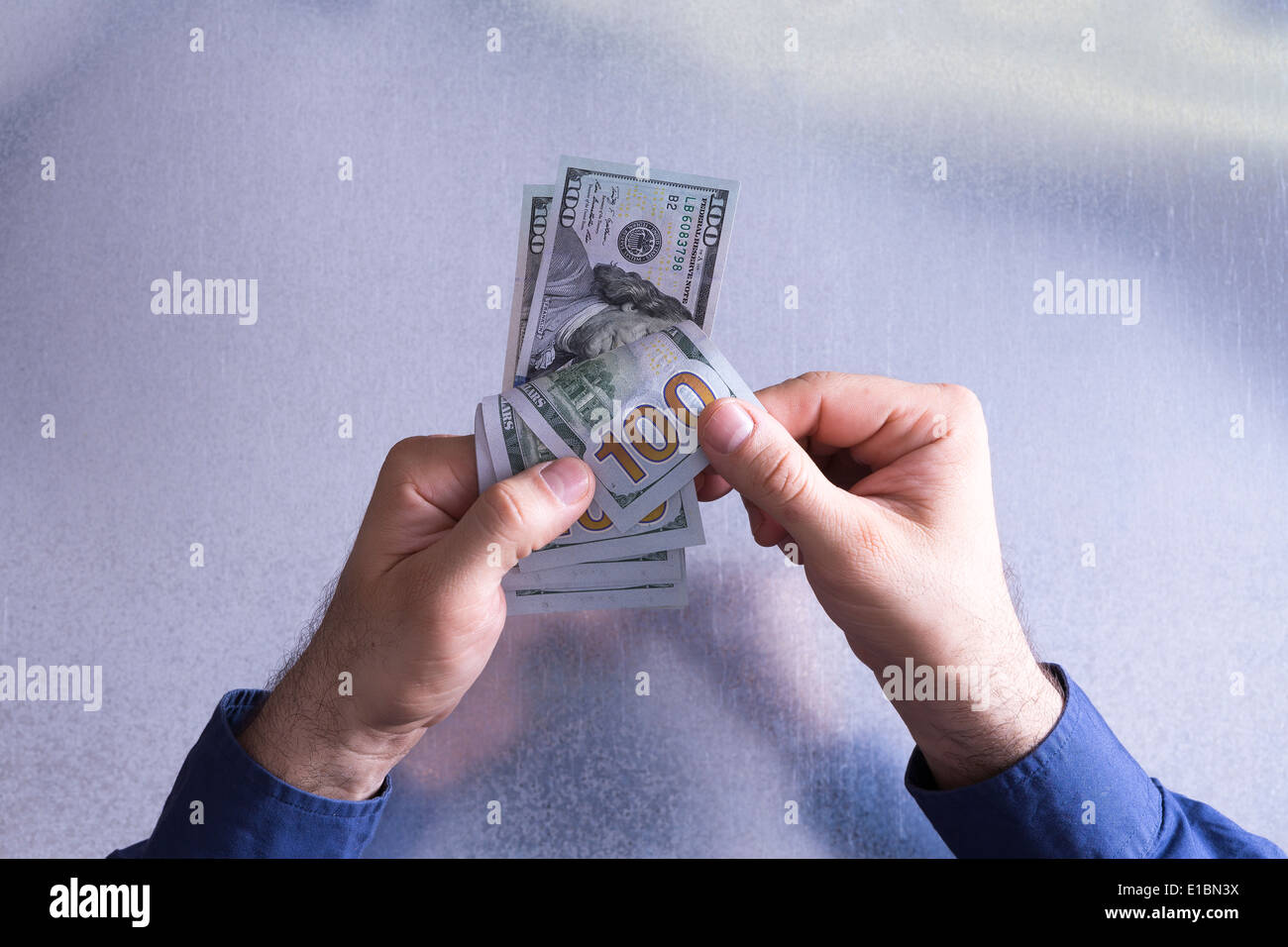 Man counting or paying out 100 dollar bills in a financial and monetary concept viewed from above with only his hands visible Stock Photo