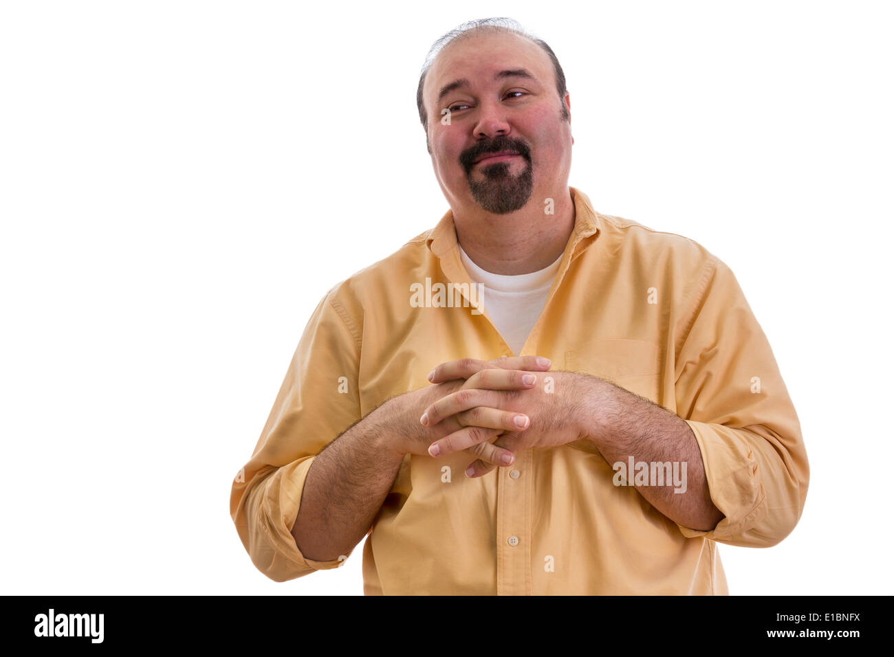 Happy overweight middle-aged man with a goatee clasping his hands over his chest and glancing sideways with a complacent express Stock Photo