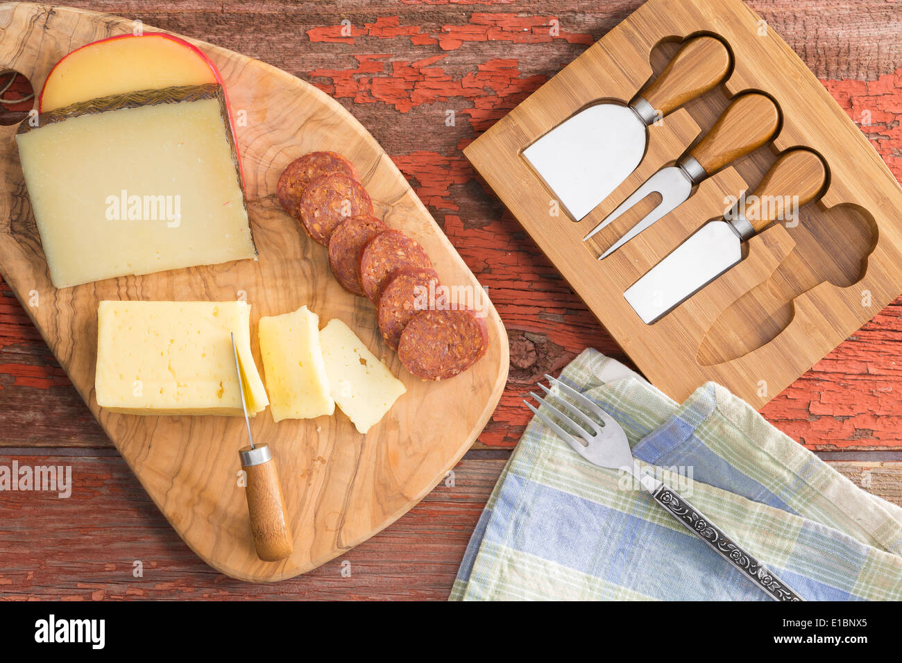 Overhead view of a cheeseboard with assorted cheeses including havarti, manchego and gouda served with sliced spicy sausage on a Stock Photo