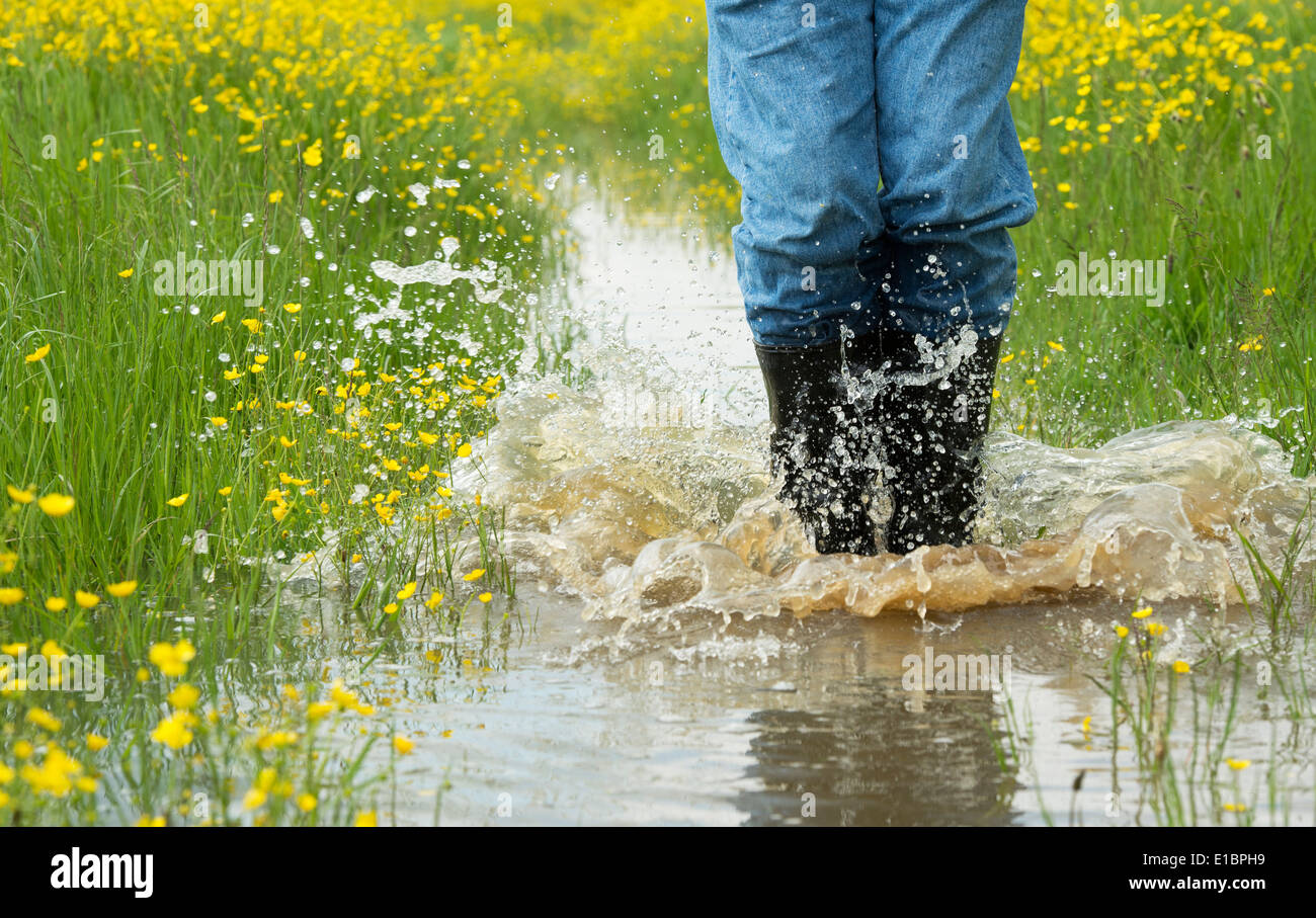 Man in wellington boots splashing water in a flooded field. England Stock Photo