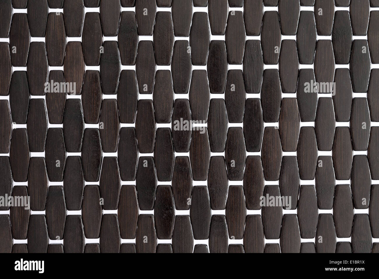 Background texture and pattern of a dark wood or bamboo mat with white cross weave detail and a repeat parallel pattern close up Stock Photo