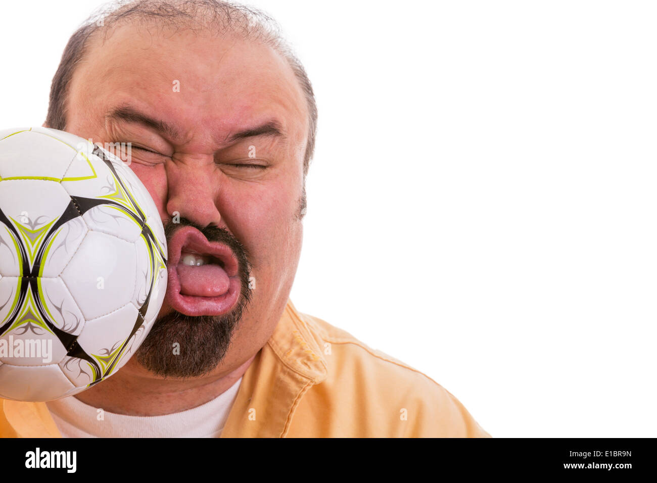 Fun picture of a middle-aged man with a goatee having the wind knocked out of him by the unexpected force of a soccer ball Stock Photo