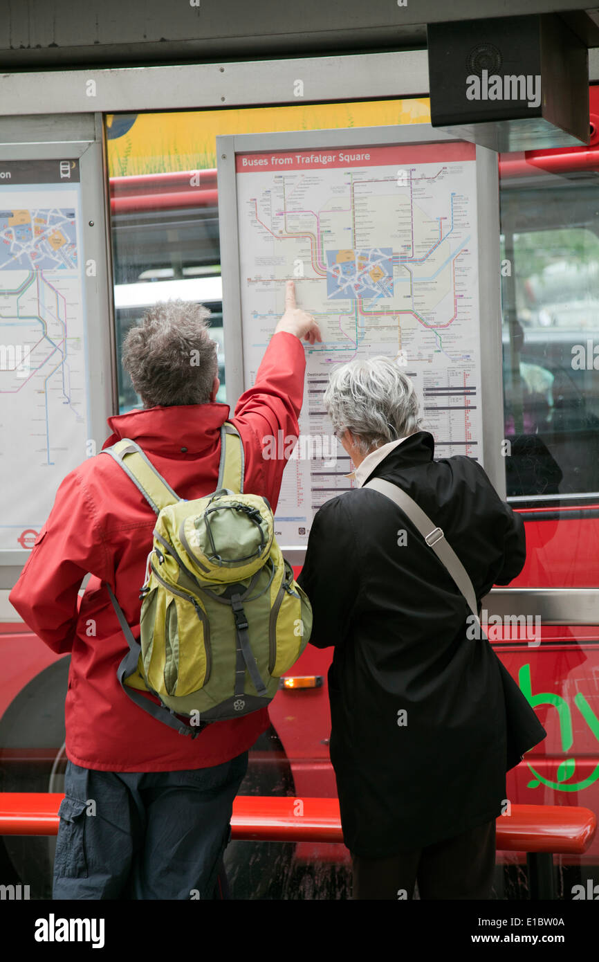 Senior Tourists Pointing out Bus Journey - London UK Stock Photo