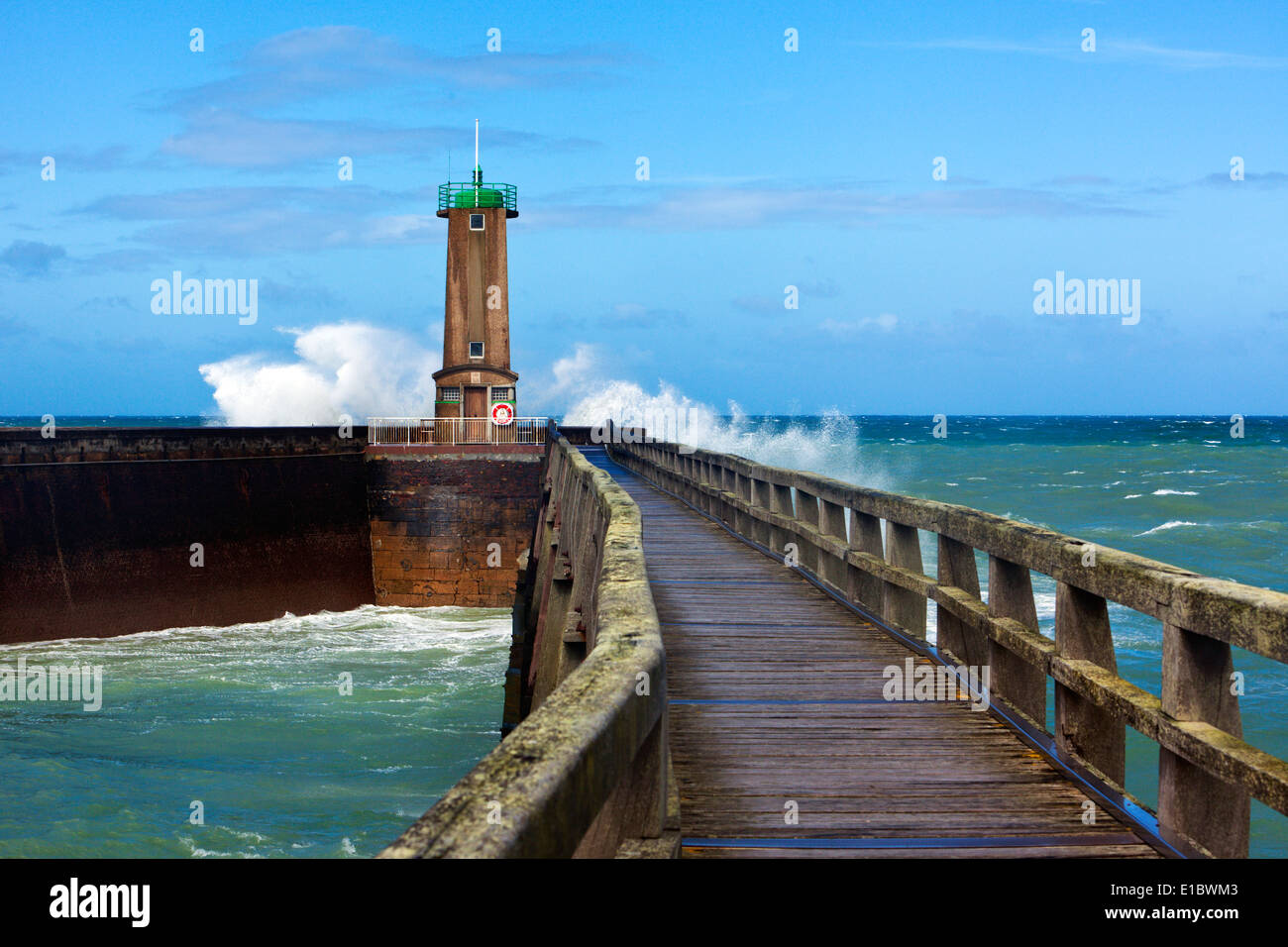 Waves crashing at the green beacon of Fecamp harbor entrance Stock Photo