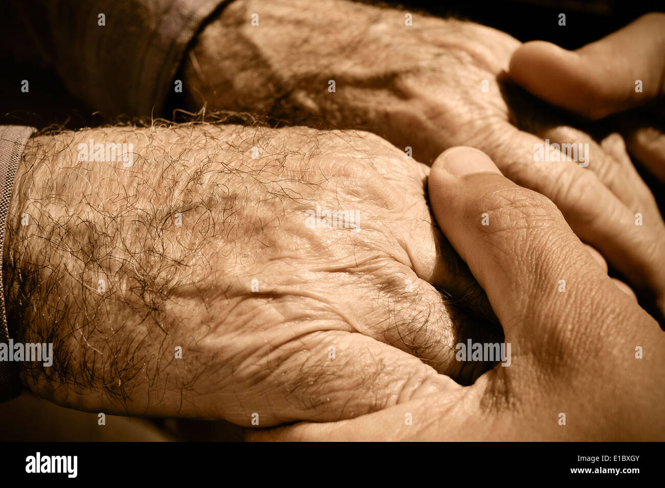 young man holding the hands of an old man Stock Photo