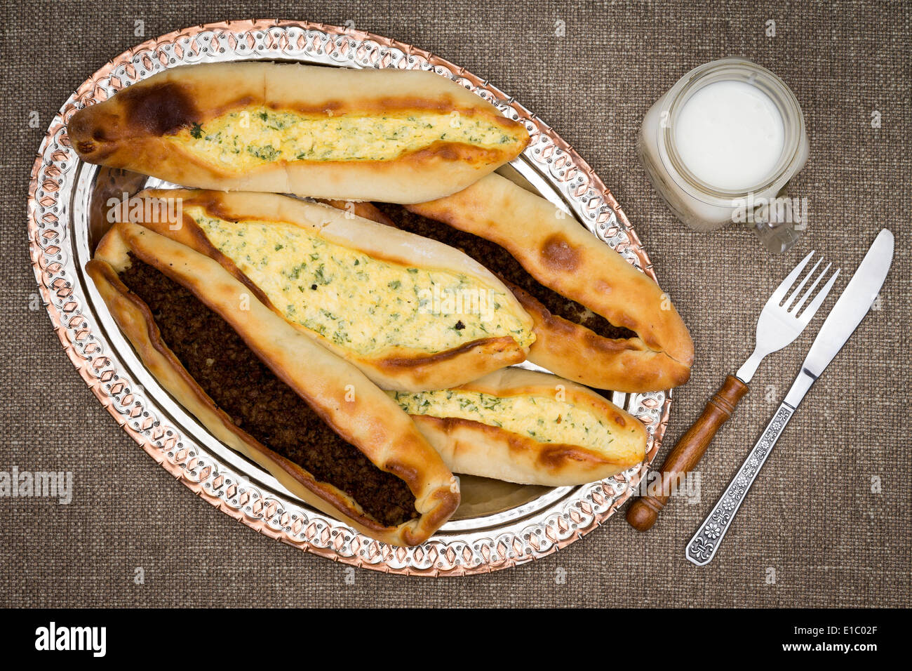 Turkish pide, a traditional unleavened flatbread , topped with ground beef and cheese and served with a glass of ayran, a Turkis Stock Photo