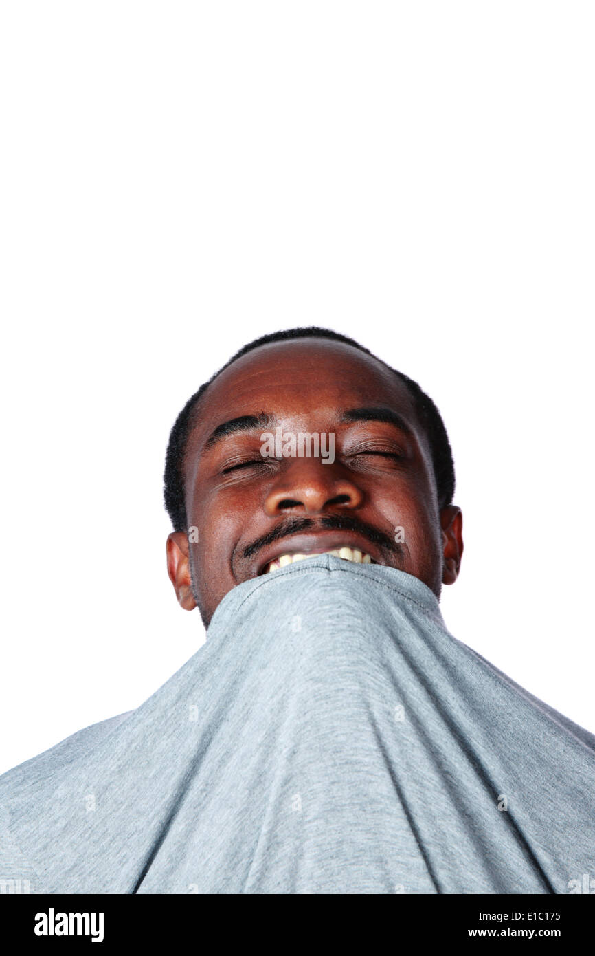 Portrait of crazy young african man biting his t-shirt over white background Stock Photo