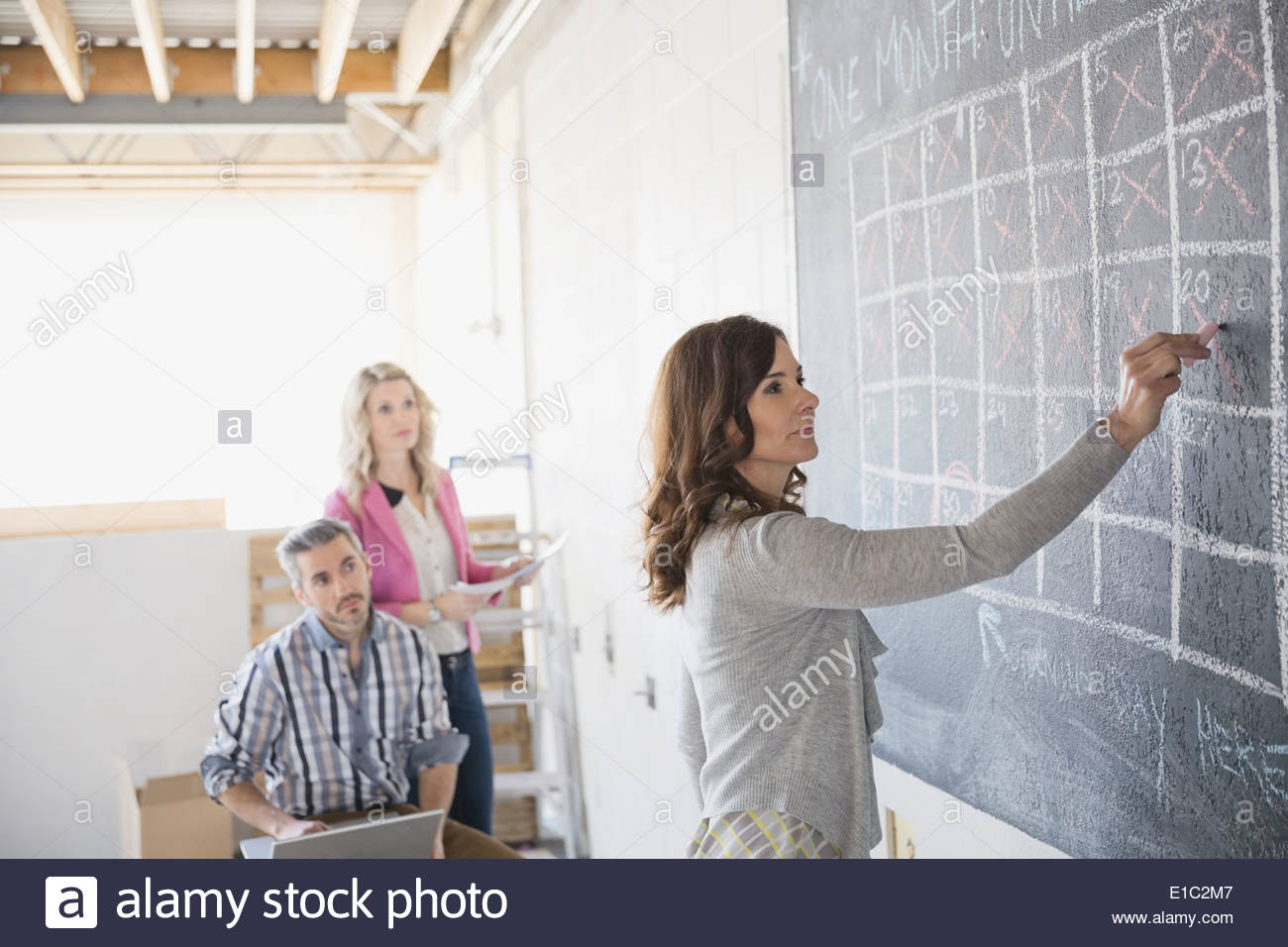 Business owners at chalkboard calendar in new office Stock Photo