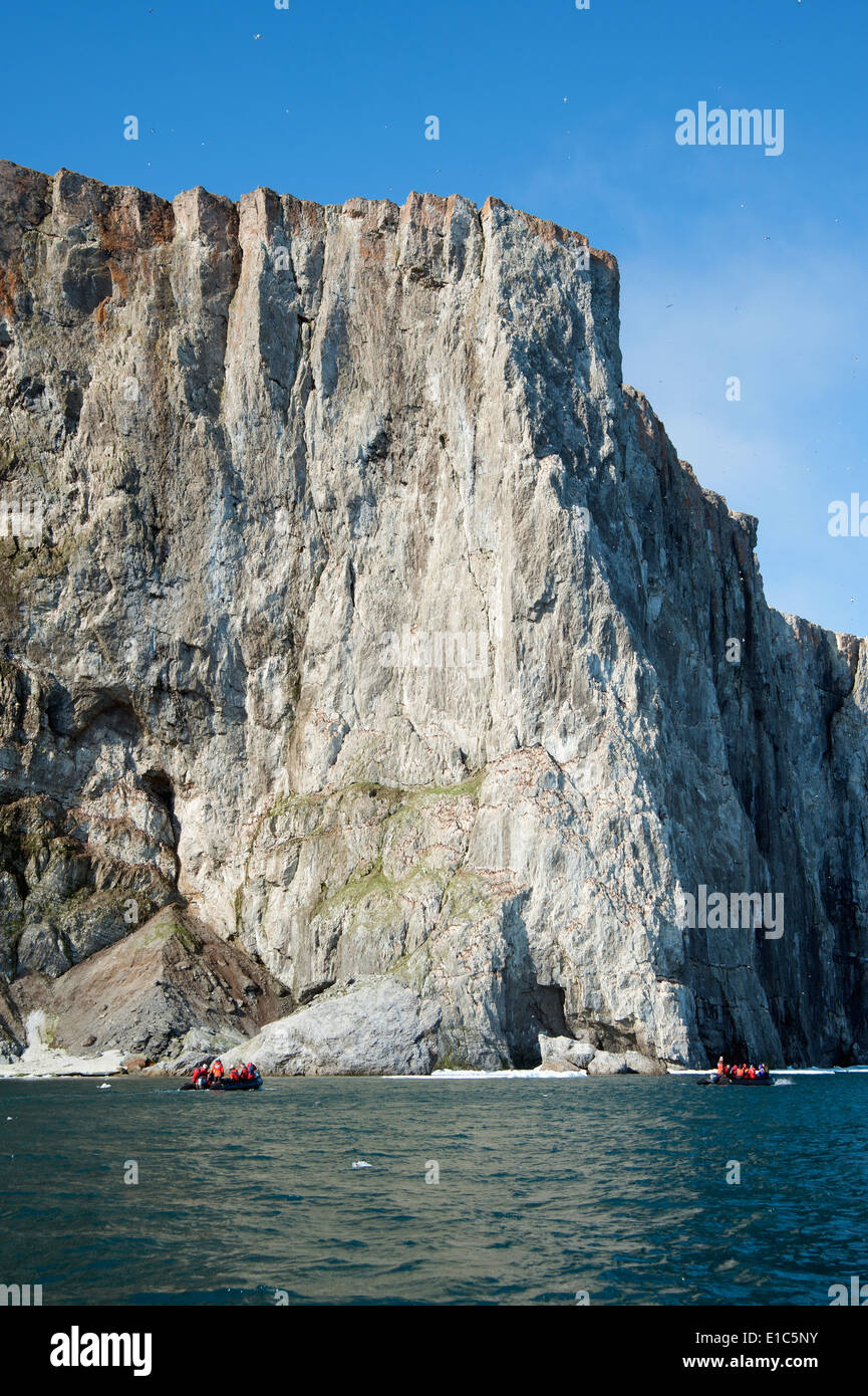 Zodiac boats with people, traveling along the cliffs in Nunavut, Canada