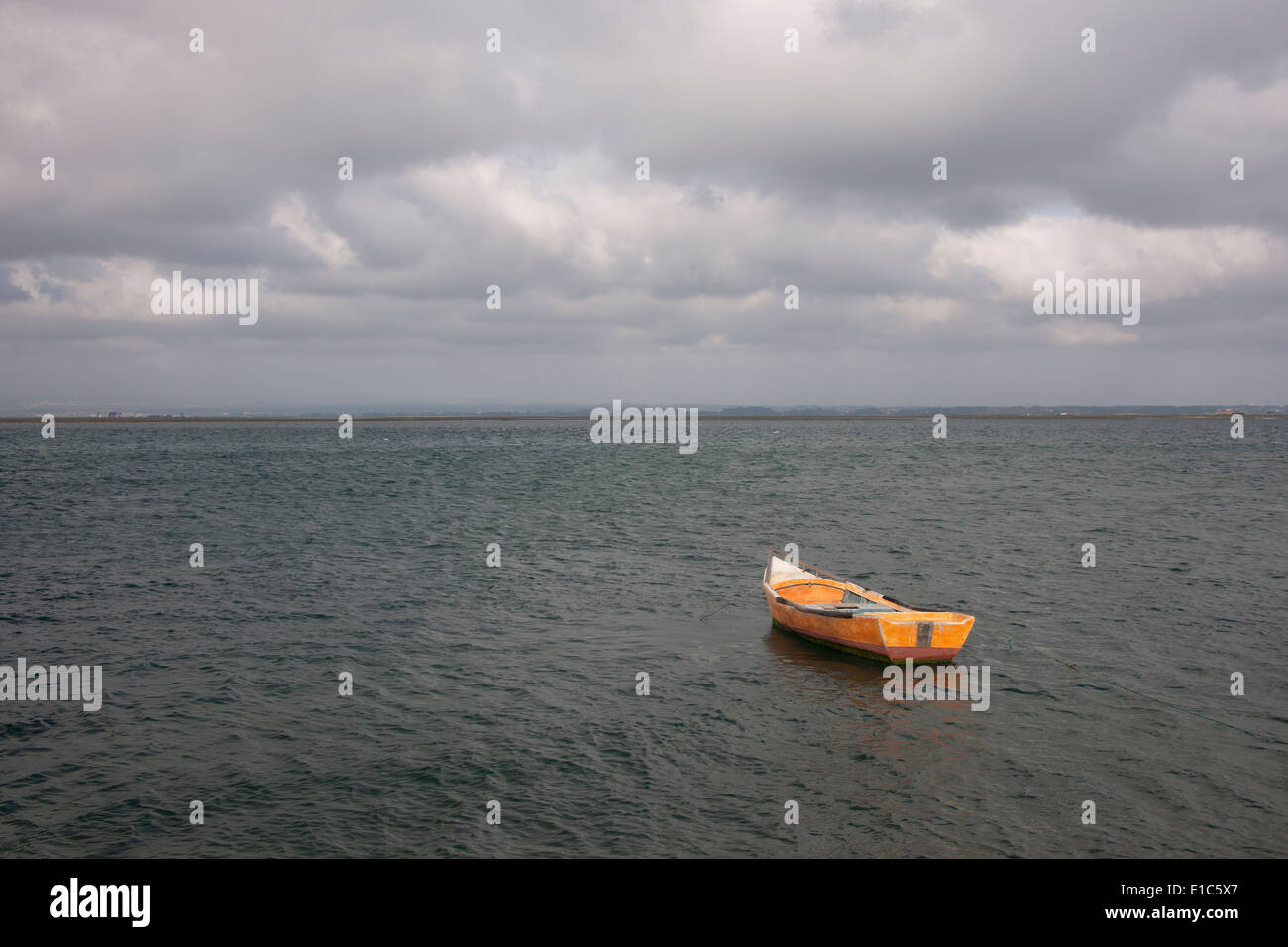 A small wooden boat moored in open water, off the Portuguese coast. Stock Photo