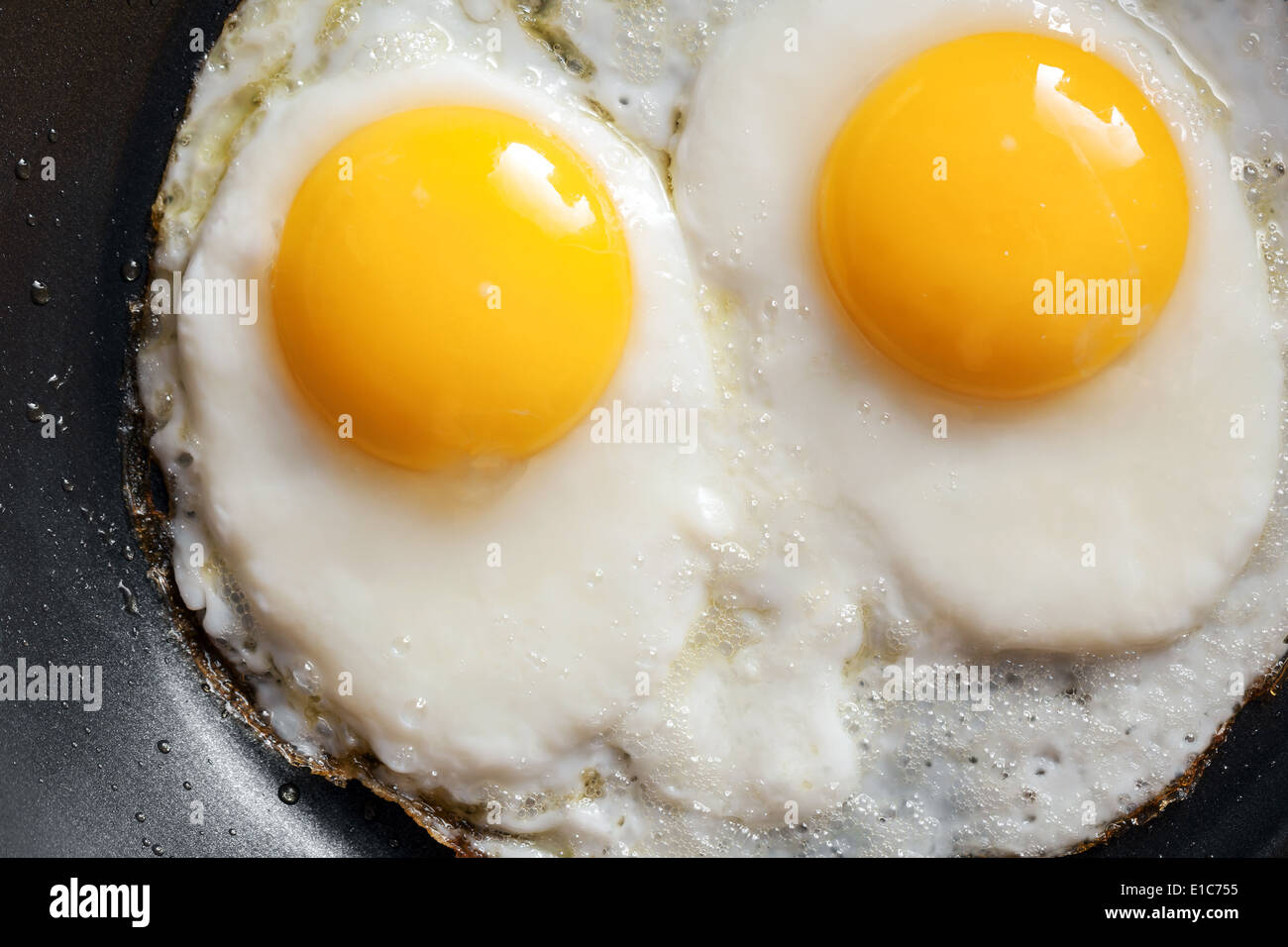 Macro photo of two scrambled eggs in black frying pan Stock Photo Alamy
