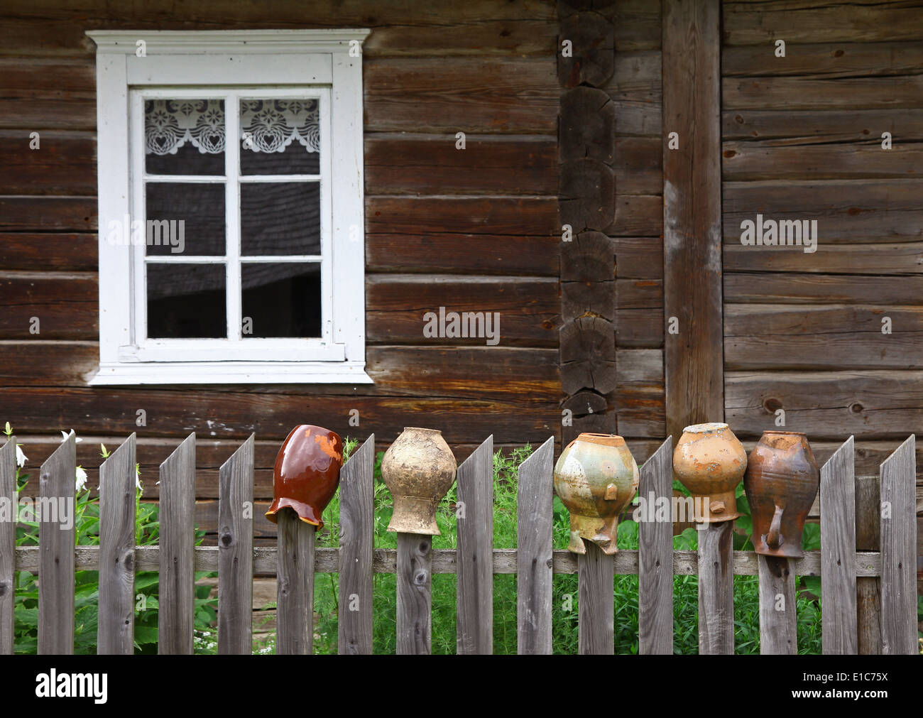 Picture of an old rural house with window and old jugs on the wooden fence Stock Photo