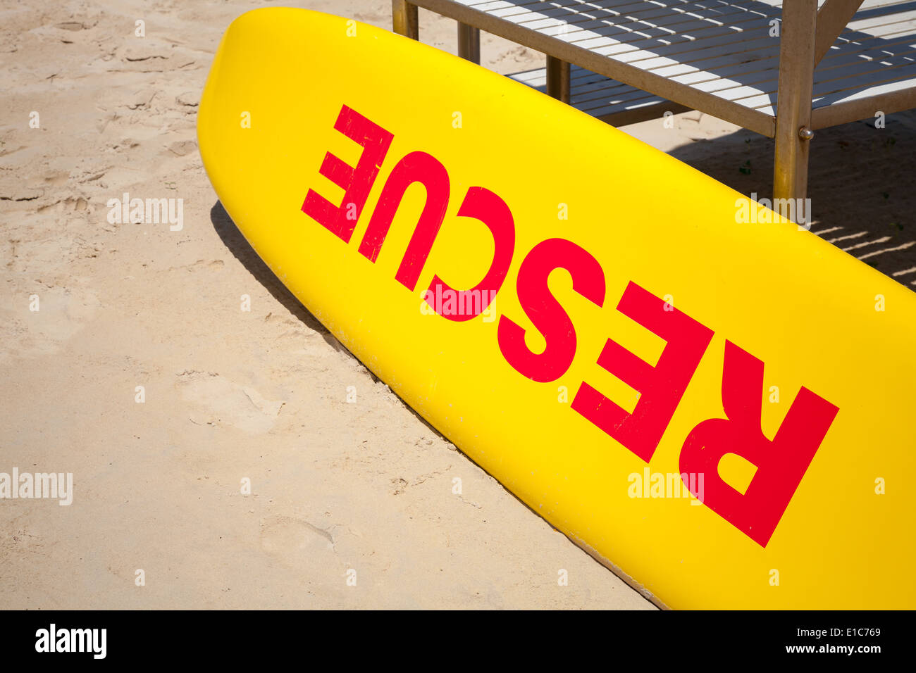 Small yellow rescue boat lays on sandy beach Stock Photo